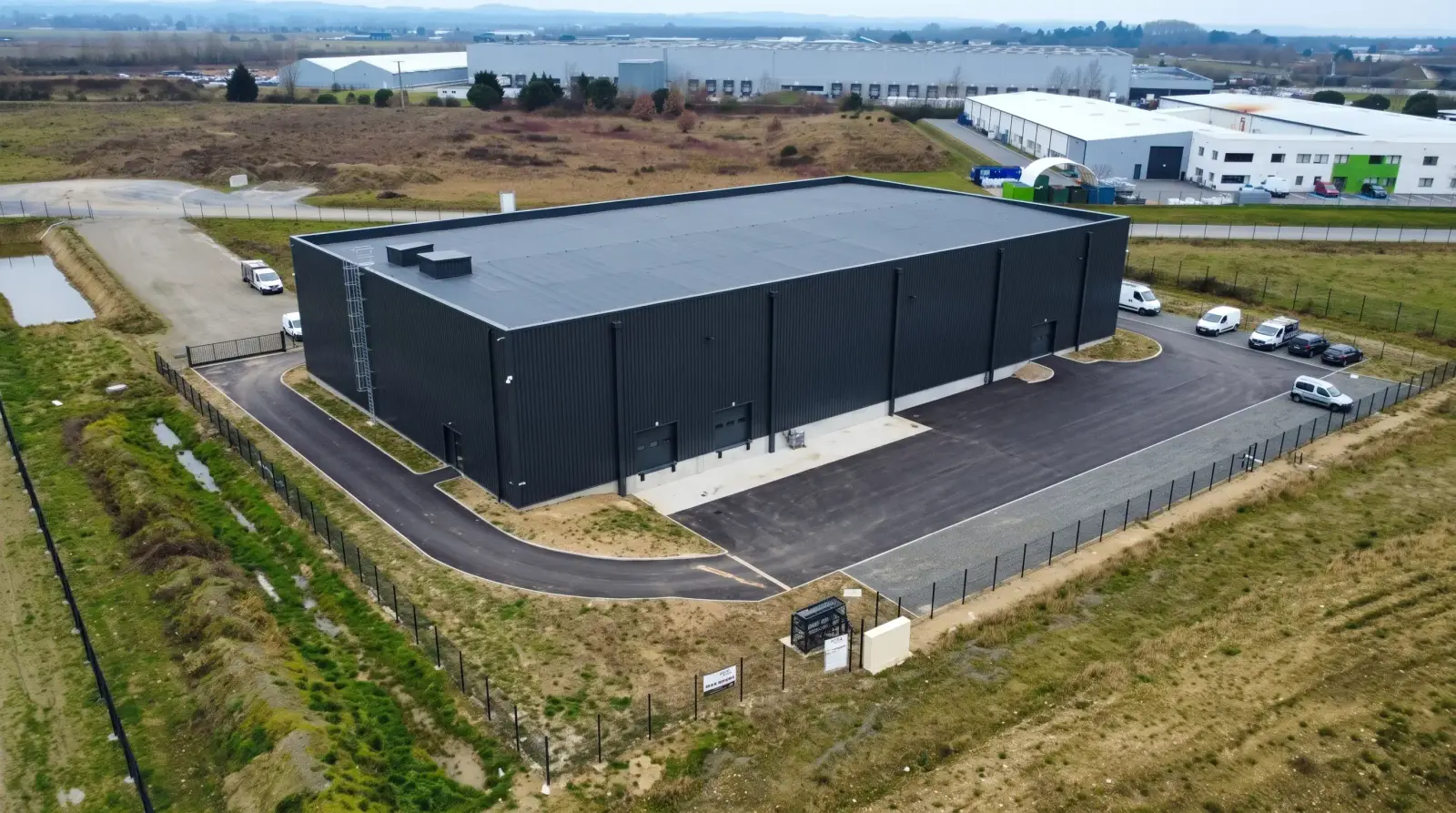 Vue aérienne d’un bâtiment d’activité à bardage noir livré par Experts Travaux