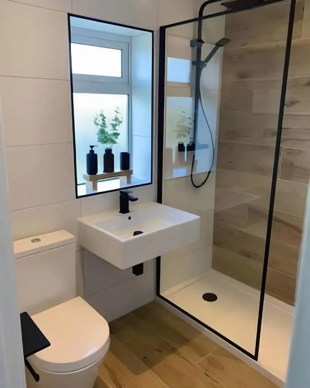 Salle de bain aux murs blancs avec douche vitrée à profilés noirs, carrelage effet bois et vasque suspendue